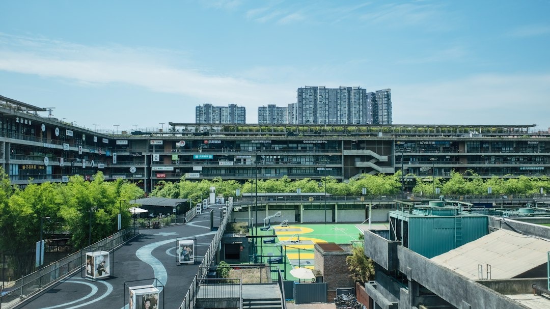 Modern concrete business complex with green terraces and a basketball court.