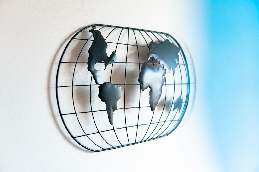 Black wireframe metal world map on a neutral wall.